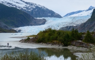 Mendenhall Glacier: A stunning view of a hiker walking by Mendenhall Glacier near Juneau, Alaska.